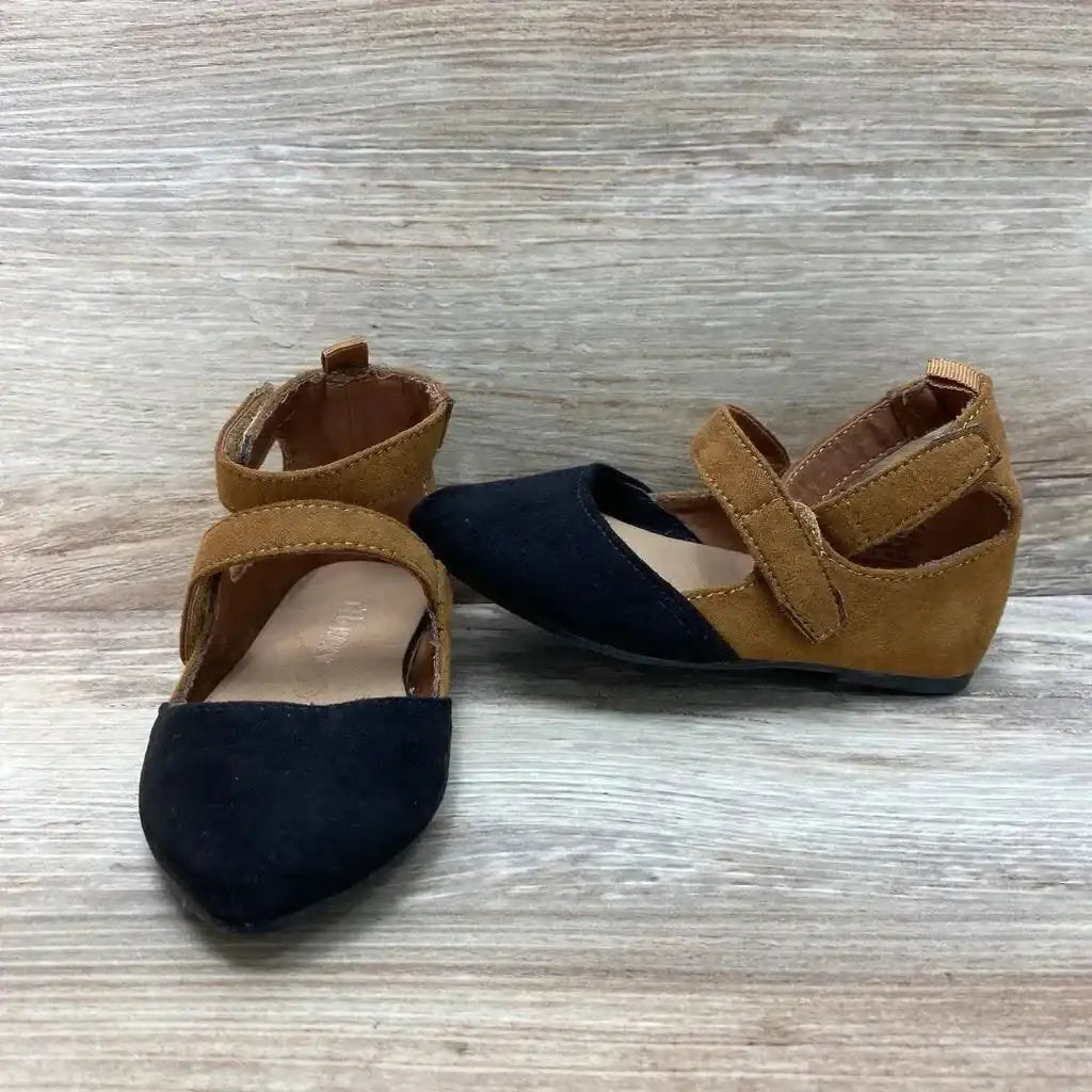 Angled view of toddler ballet flats with black suede toe and brown suede body, ankle Velcro strap on wood background