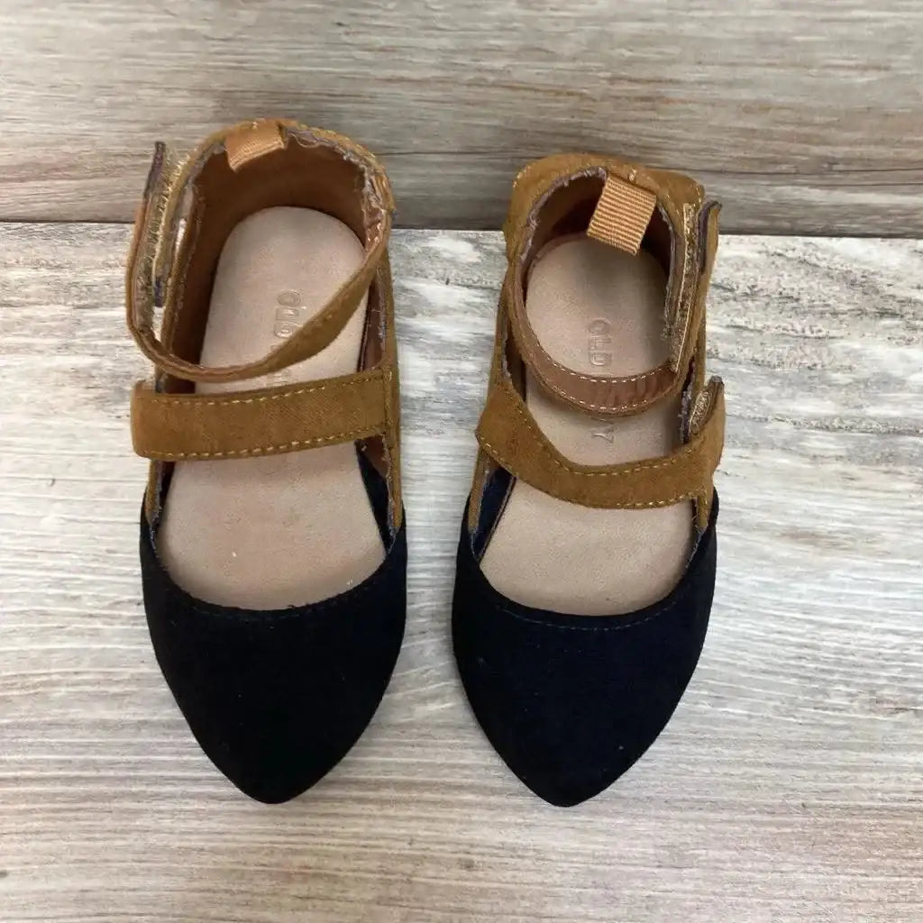 Top-down view of toddler Old Navy ballet flats showing pointed black toes and brown suede Velcro ankle straps on light wood background