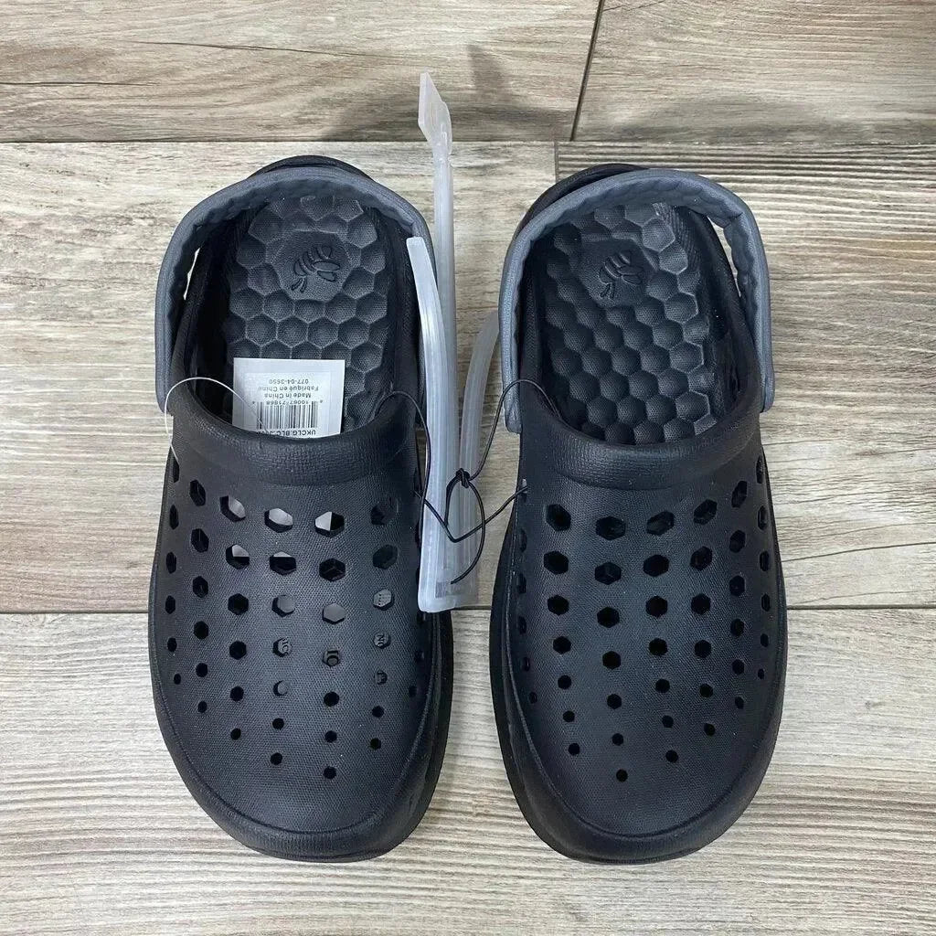 Top-down view of black Joybees clogs size 2Y showing perforated upper, textured footbed and heel strap on light wood floor