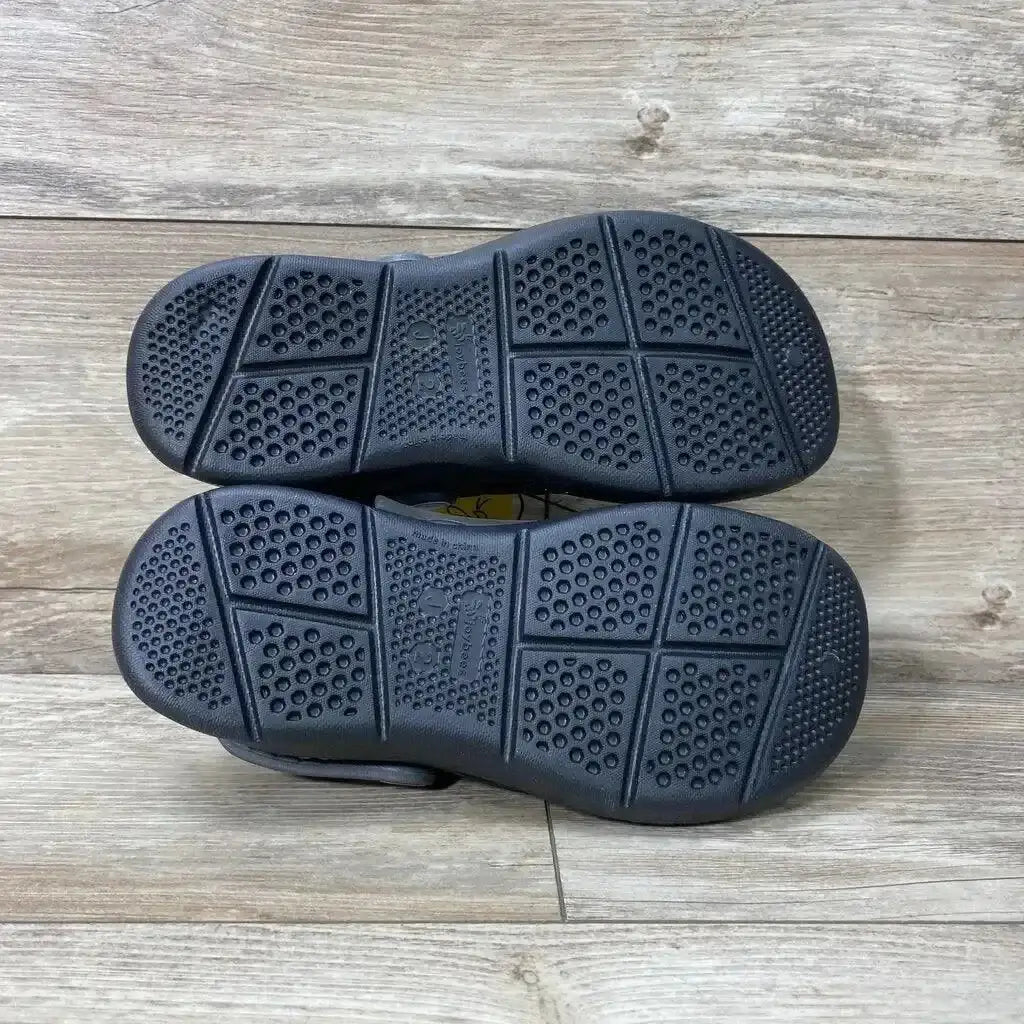 Top-down view of size 2Y Joybees unisex black varsity clogs showcasing textured non-slip soles on light wood floor