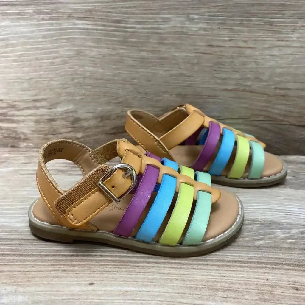 Side view of Cat and Jack toddler sandals size 5C with tan footbed, rainbow straps, and buckled ankle strap on wooden background