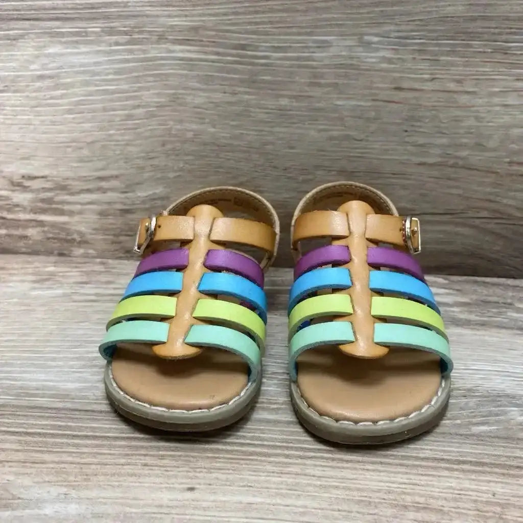 Front view of Cat and Jack toddler sandals size 5C with tan footbed, rainbow leather straps, and buckle on wood floor