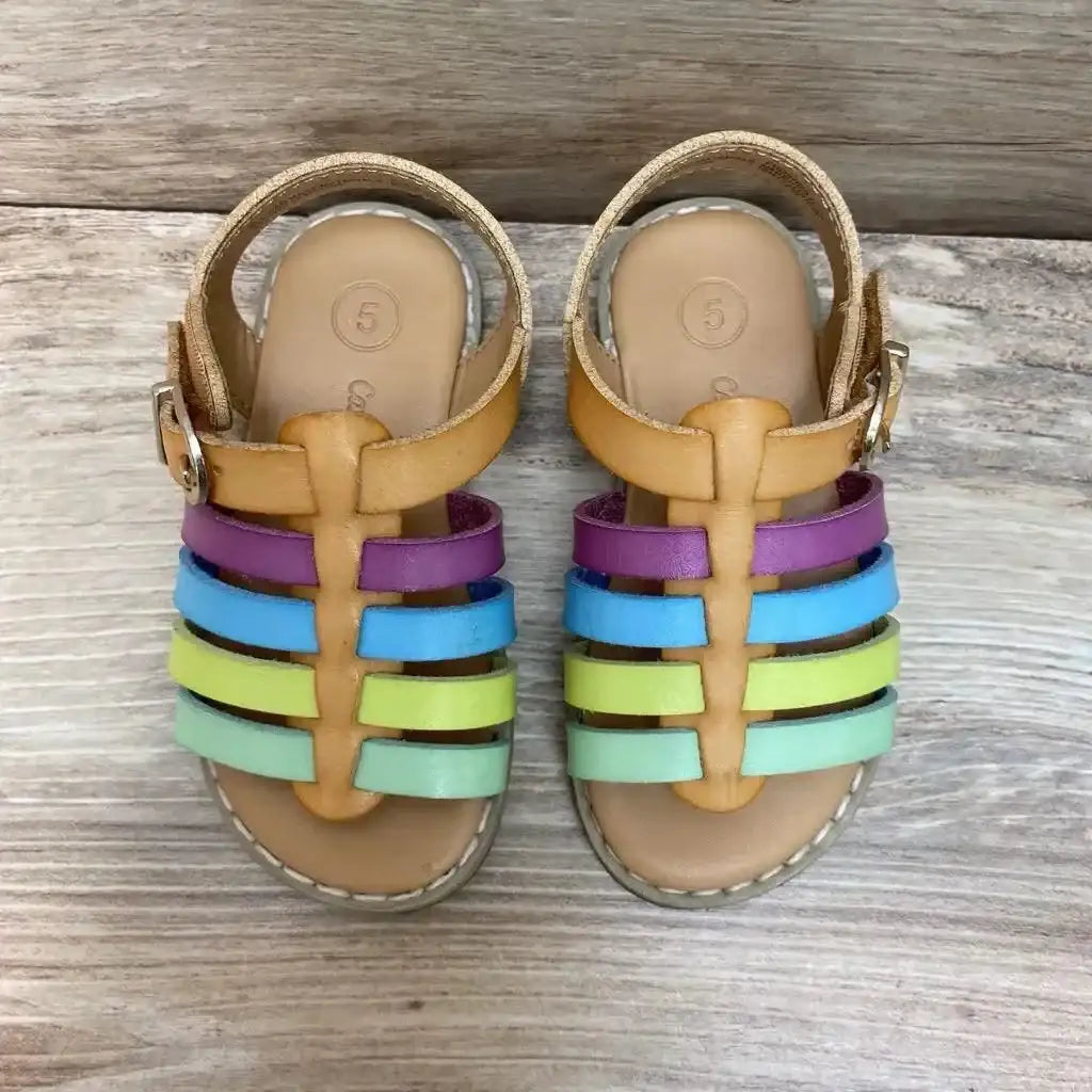 Top view of Cat and Jack toddler sandals, tan base with purple, blue, lime, and mint straps, size 5 stamped on insole on light wood background