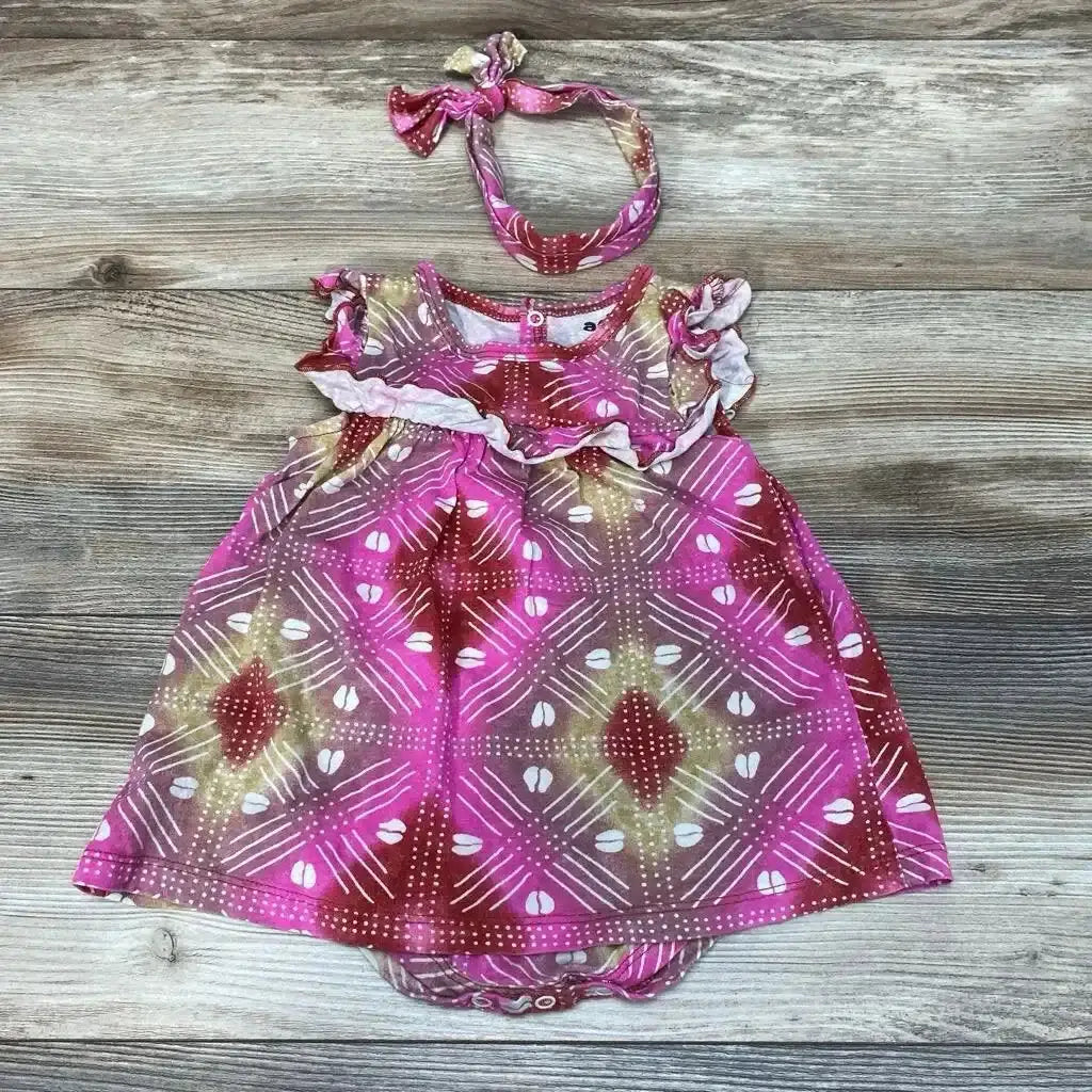 Flat lay of pink patterned 2-piece baby bodysuit dress size 6-9 months with ruffle sleeves and matching headband on wood background