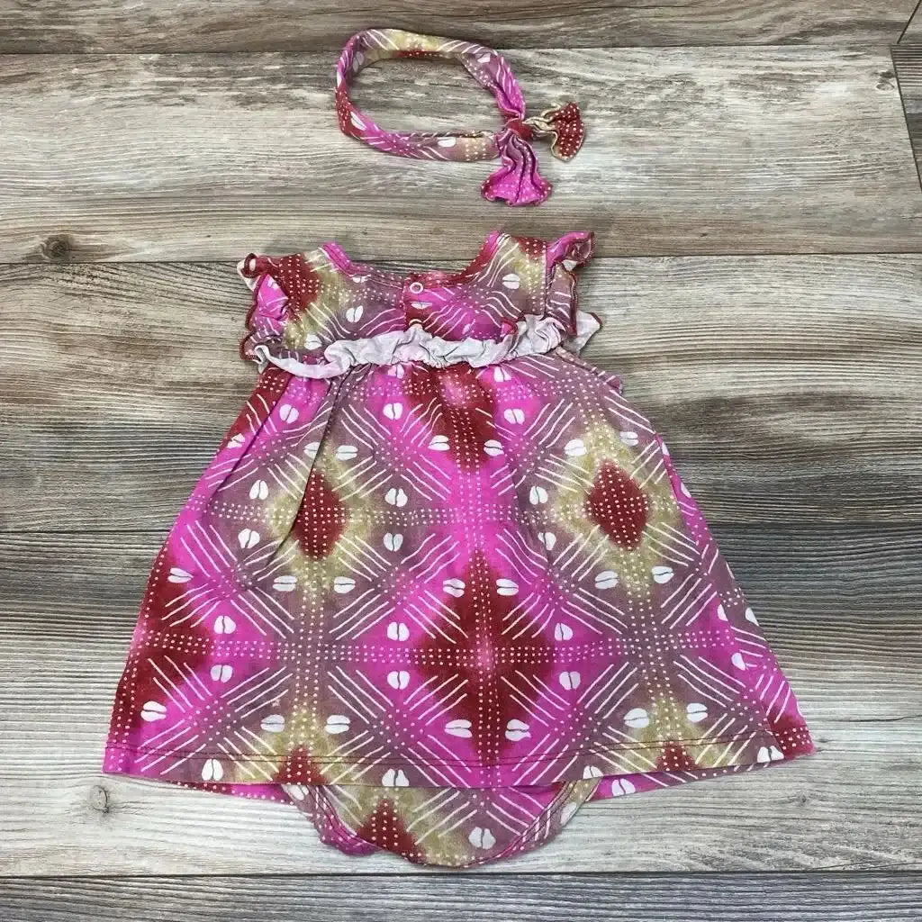 Flat lay of ade and ayo 2pc Bodysuit Dress and Headband sz 6-9m showcasing pink geometric print ruffle bodice and matching tied headband on wood plank background