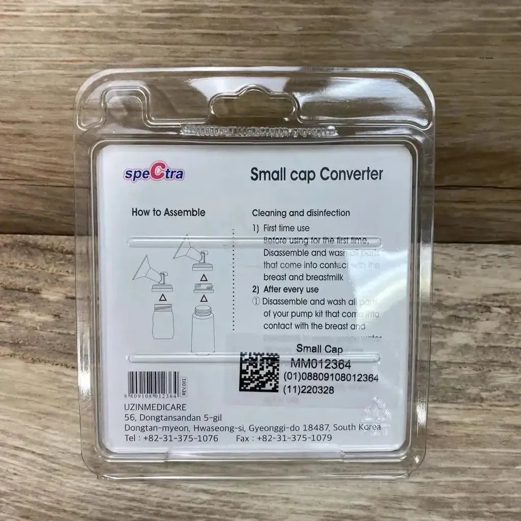 Back of NEW Spectra Small Cap Converter clamshell package showing assembly diagram and cleaning instructions on wood plank floor