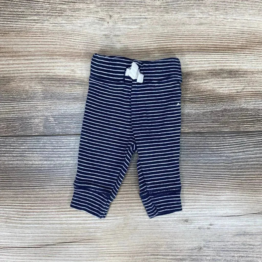 Flat lay of navy and white striped Carter's preemie pants with elastic waistband and small white bow on wood background