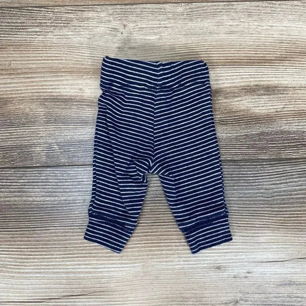 Top-down view of Carter's preemie navy and white striped pants showing fold-over waistband and cuffed legs on wood background
