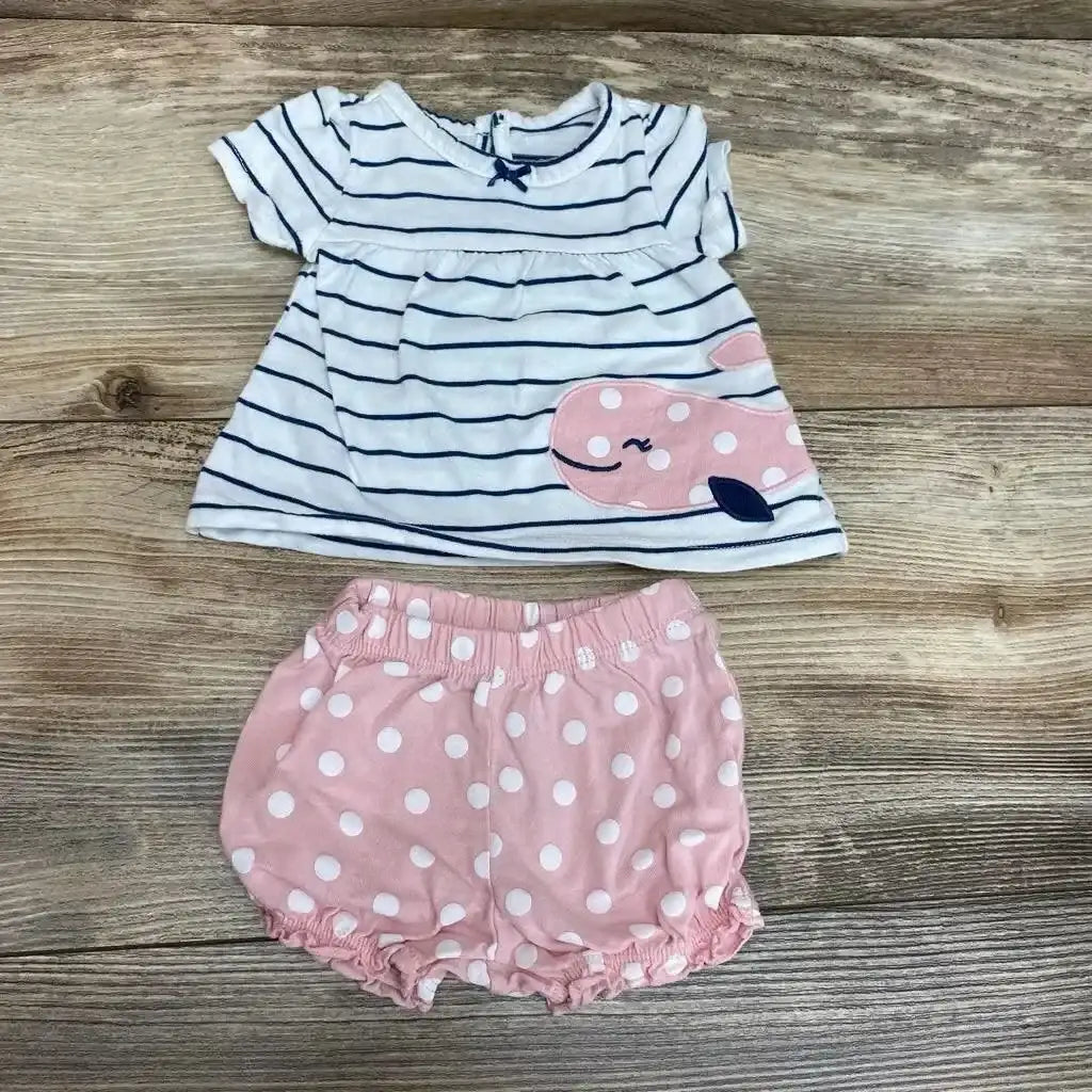 Flat lay of Carter’s newborn white striped top with whale applique and pink polka-dot elastic shorts on wooden surface