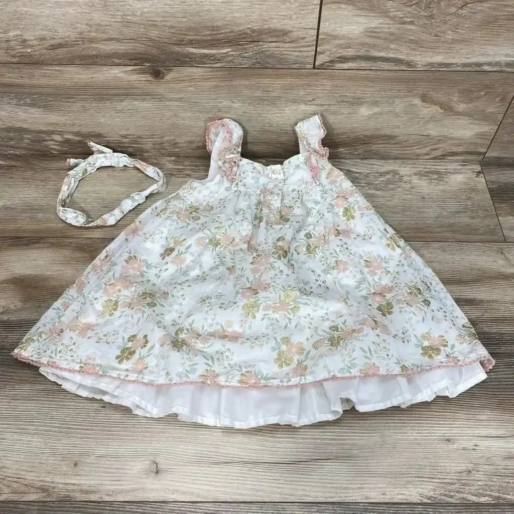 Flat lay of 3T white floral sleeveless dress with matching headband, ruffled straps and layered underskirt on wood floor