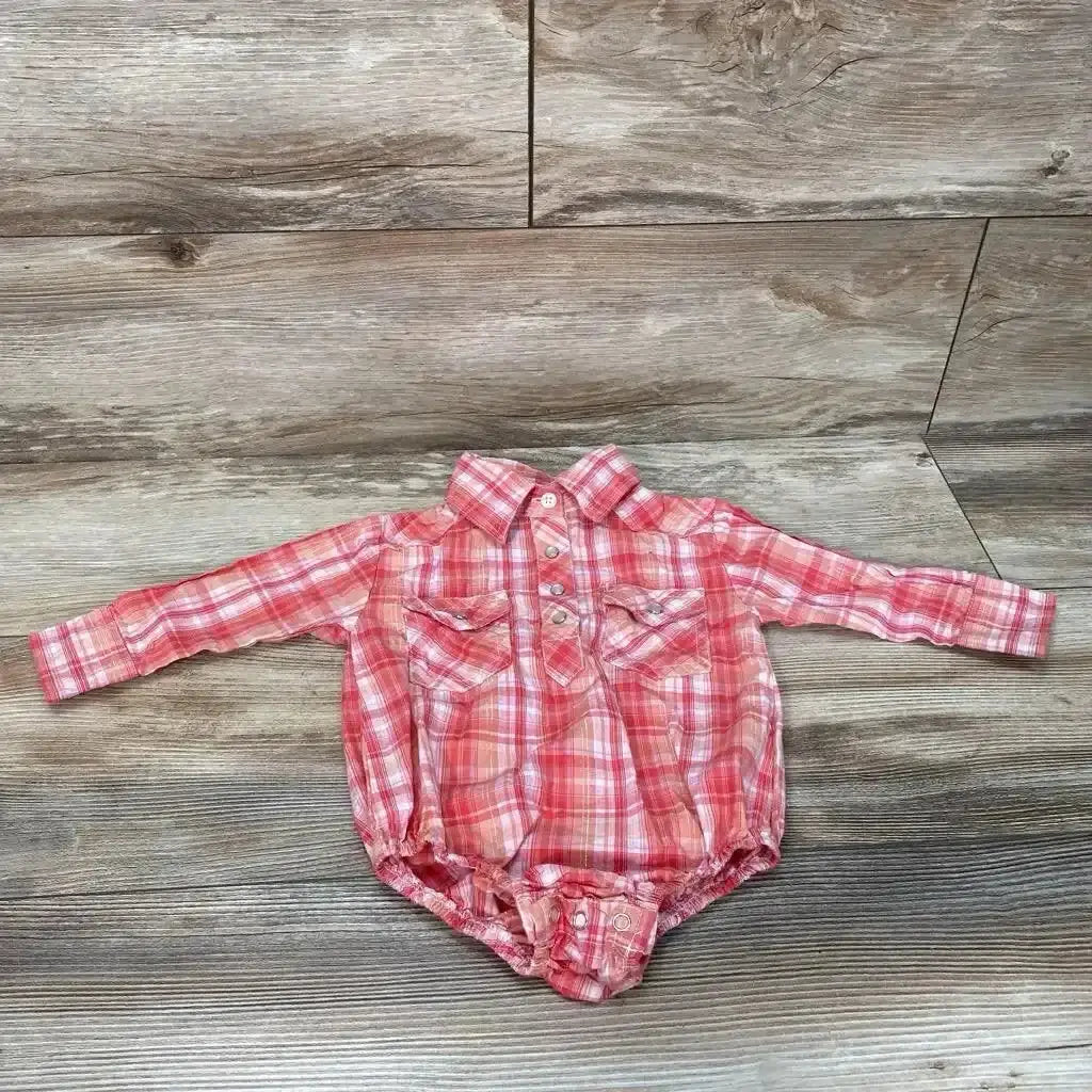 Front view of Cowgirl Legend plaid bodysuit, size 6 to 9 months, showcasing two front chest pockets with a wood grain background