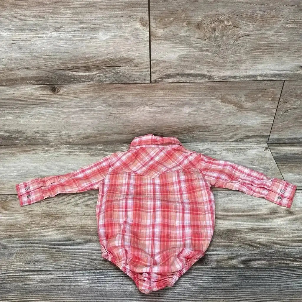 Back view of Cowgirl Legend plaid bodysuit in size 6-9 months showing pink-red plaid and long sleeves on a wood-look floor