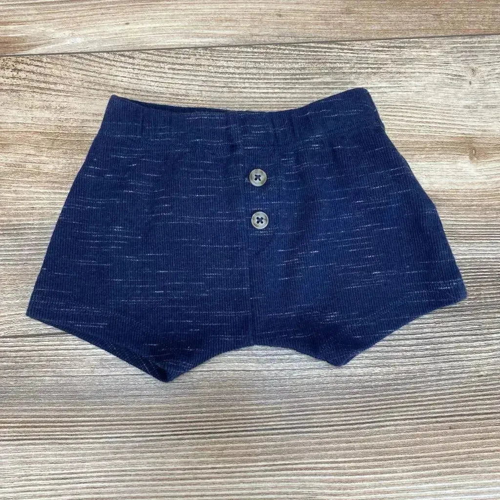 Flat lay of navy knit baby shorts size 3-6m showing elastic waistband and two front buttons on wood background