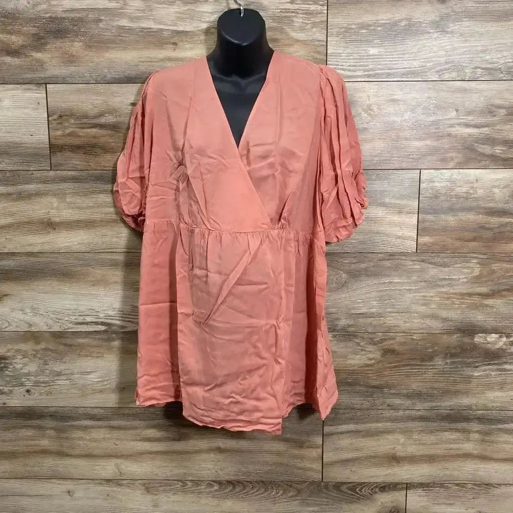 Front view of coral maternity wrap top on mannequin with V neck, puff sleeves and empire waist against wood plank background