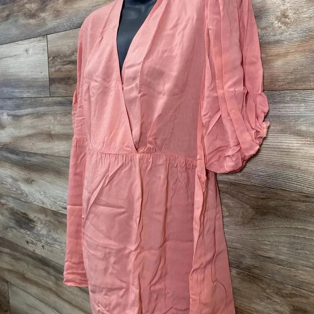 Front view of coral Gap maternity puff sleeve wrap top showing deep V neck, empire waist with tie sash on wood background