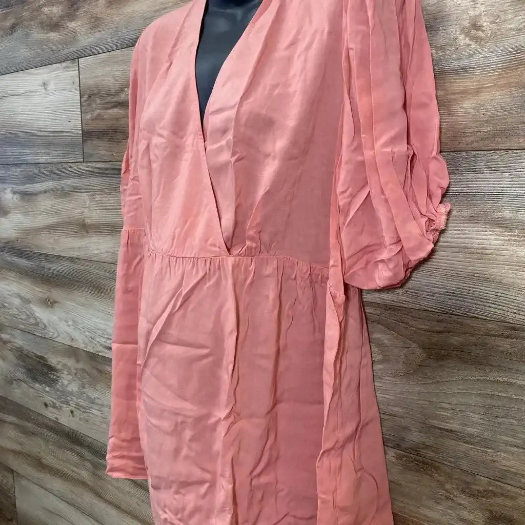 Front view of coral Gap maternity puff sleeve wrap top showing deep V neck, empire waist with tie sash on wood background