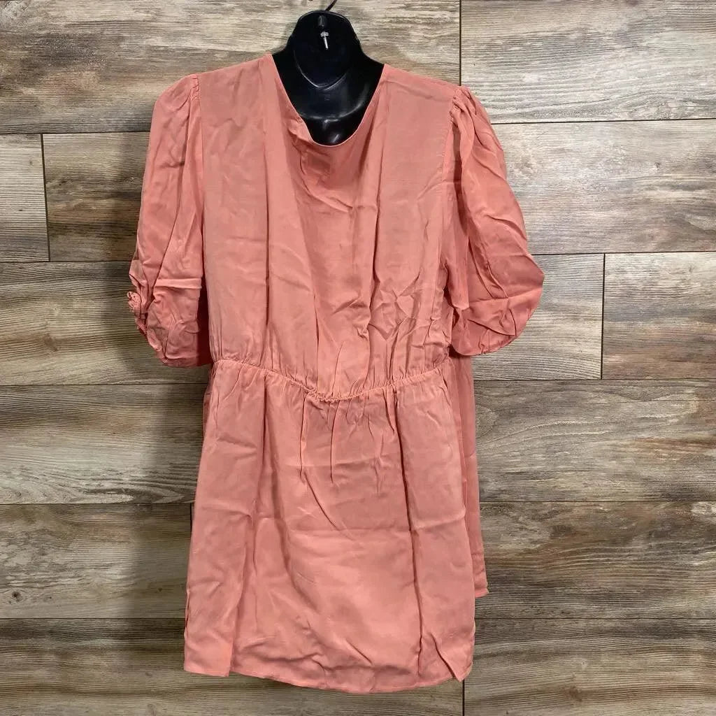 Front view of coral Gap maternity wrap top, size XL, with puff sleeves and elastic waist on black hanger, wood background