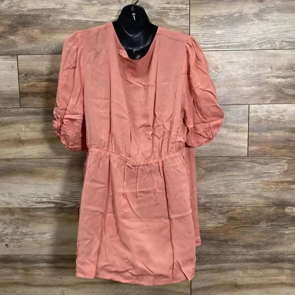 Front view of coral Gap maternity wrap top, size XL, with puff sleeves and elastic waist on black hanger, wood background