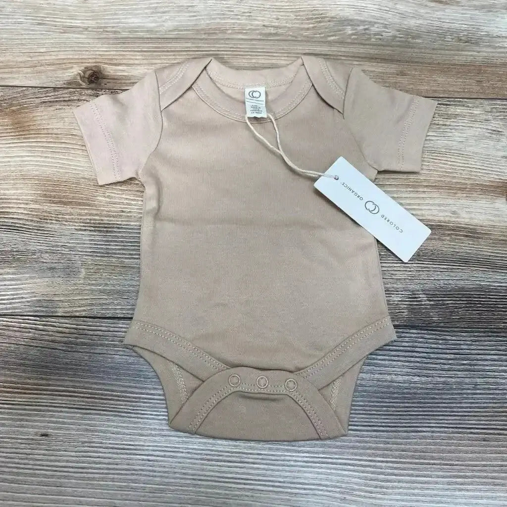 Flat-lay of Clay Colored Organics newborn short-sleeve bodysuit showing front with three crotch snaps and hang tag on wood background