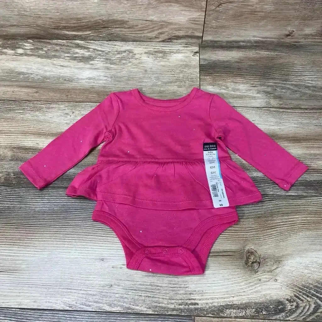 Flat lay of pink long-sleeve skirted bodysuit size 6M showcasing peplum skirt and snap crotch closures on wood floor background