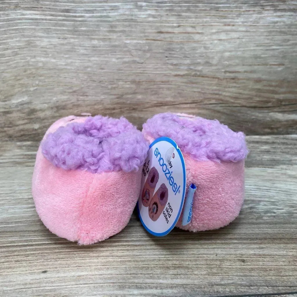 Front view of pink Snoozies baby slippers size 5c/6c showing purple faux-fur cuff and plush texture on wood background