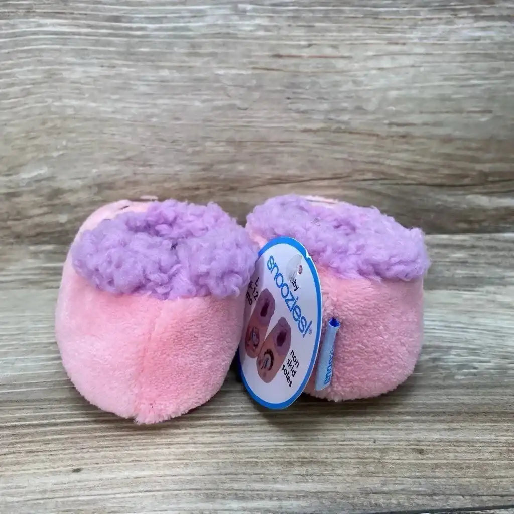 Front view of pink Snoozies baby slippers size 5c/6c showing purple faux-fur cuff and plush texture on wood background
