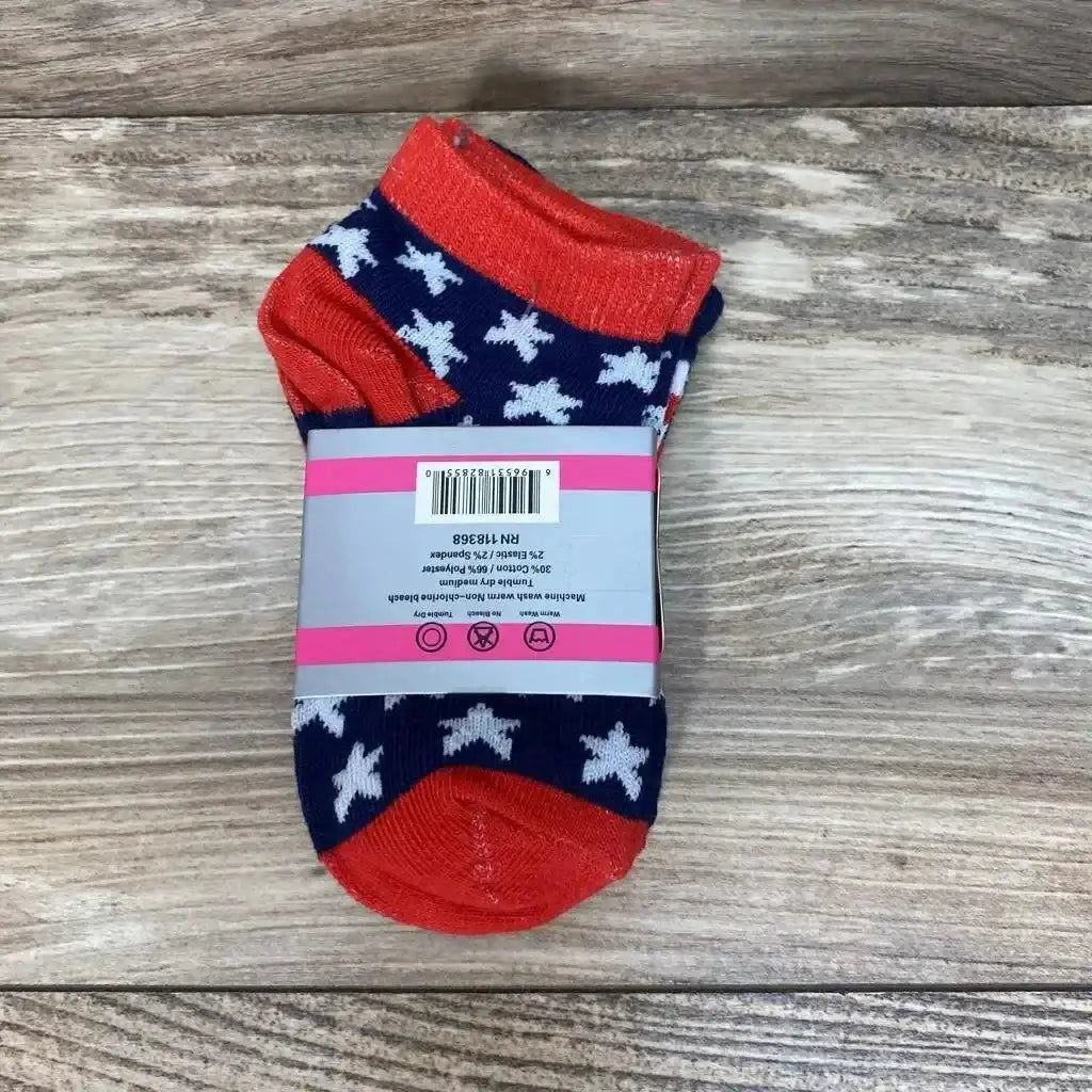 Top-down view of toddler ankle socks size 2-3 showcasing navy star pattern with red cuffs and toes and paper band packaging on a wood floor