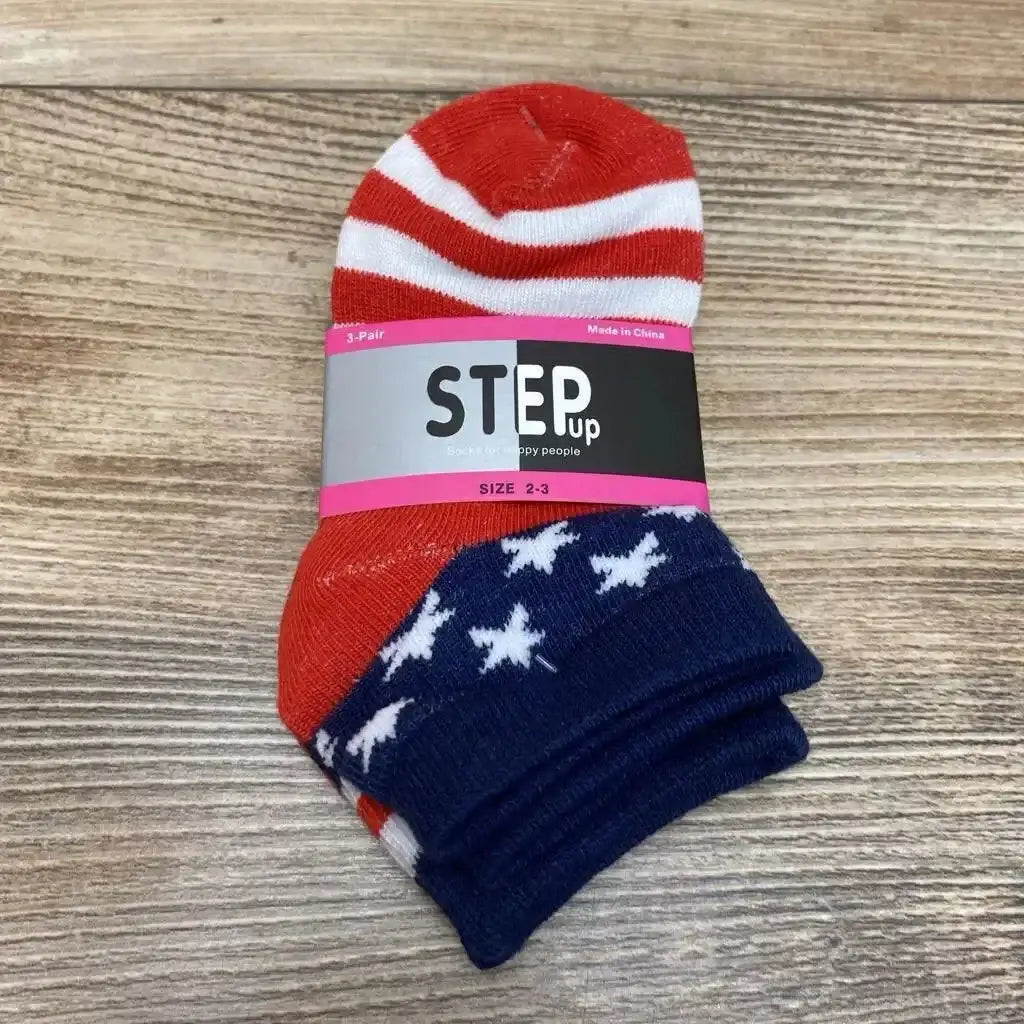 Top-down view of toddler socks showing red and white stripes and navy stars with STEP up label SIZE 2-3 on wood
