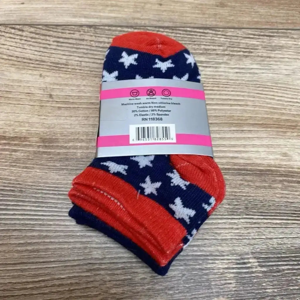 Top view of 3-pack baby socks size 2-3 showing navy socks with white star pattern and red toes and cuffs on a wood surface
