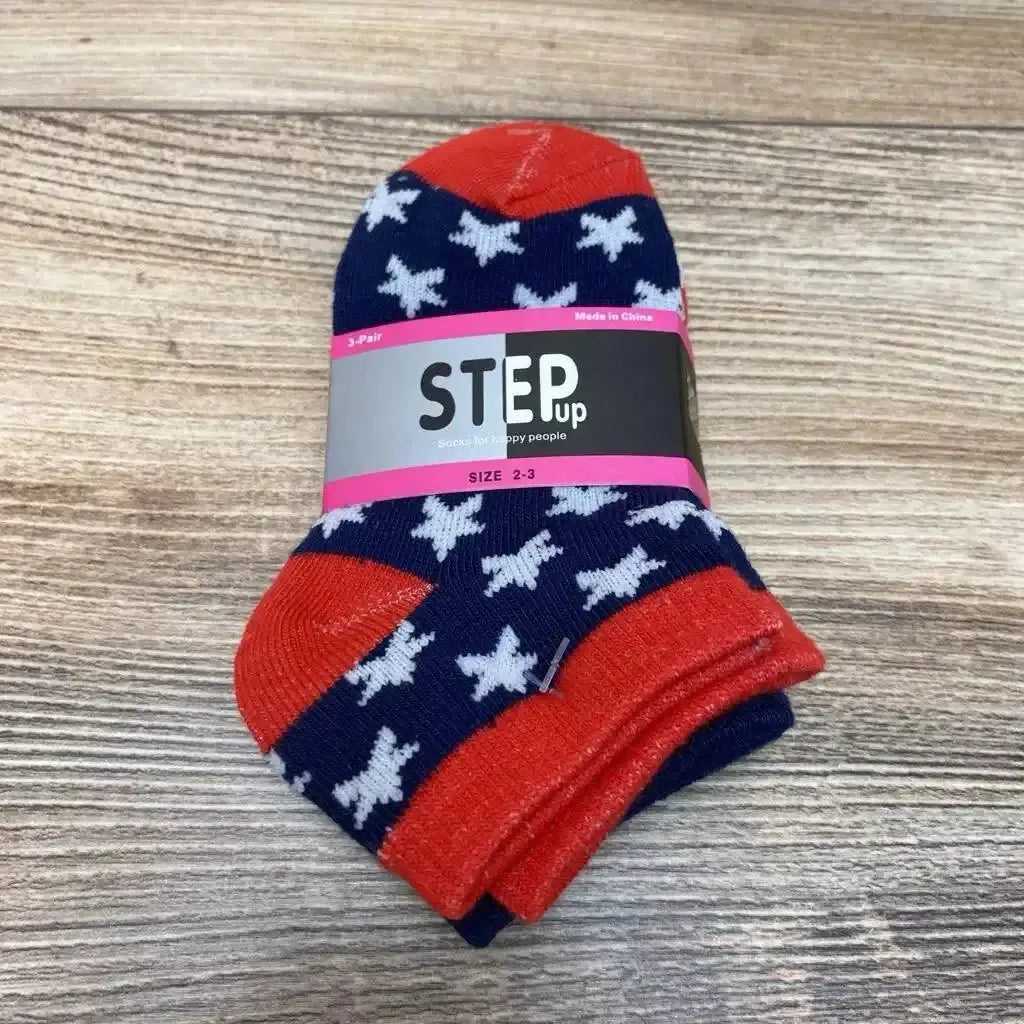 Top view of folded navy baby socks with white stars, red toes and cuffs, STEP up label reading size 2-3 on wood surface