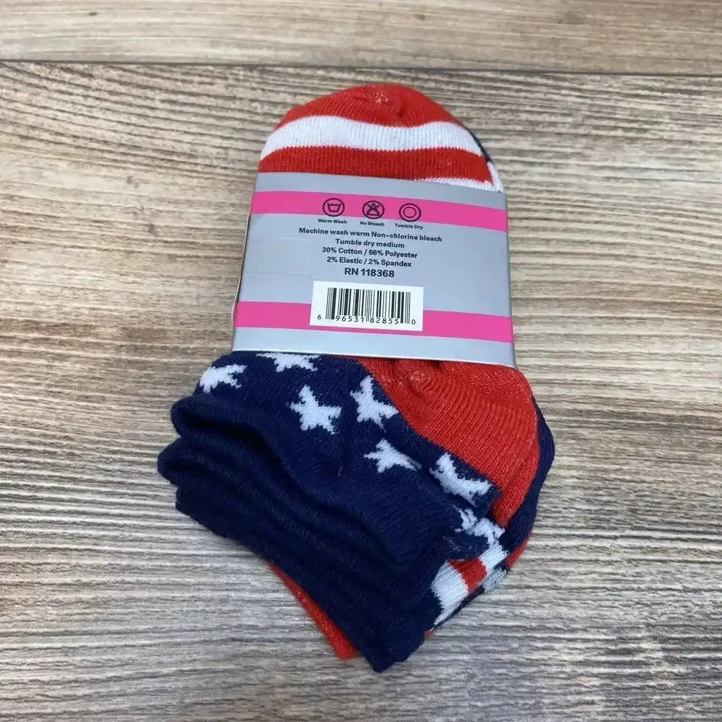 Top-down view of 3-pack toddler socks (size 2-3) in red, white, and navy with stars and stripes pattern, folded with paper label on wood surface