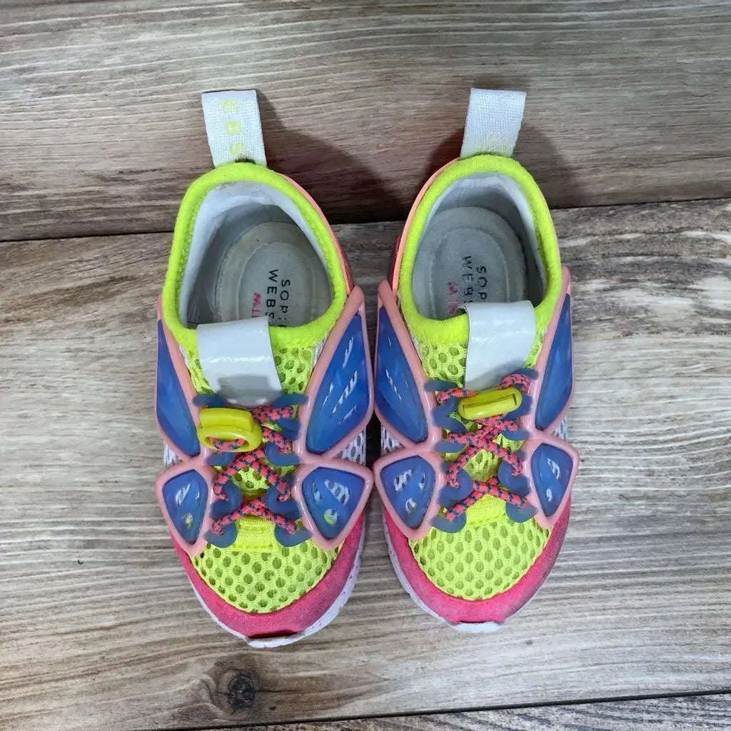 Top down view of Sophia Webster Mini Chiara toddler sneakers with blue wing overlays, neon mesh and pink trim on wood