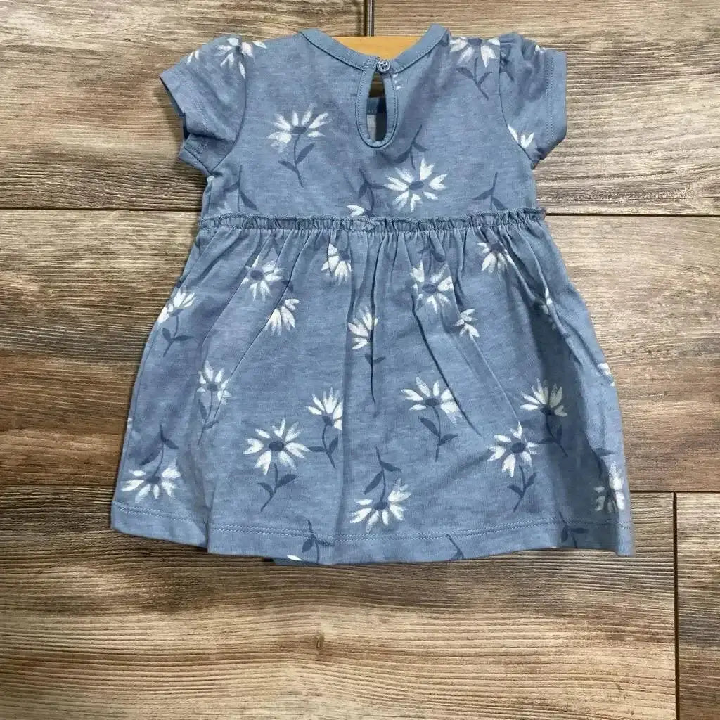 Flat lay of blue floral bodysuit dress size 3M showing gathered waist, short sleeves, and white daisy print on wood floor