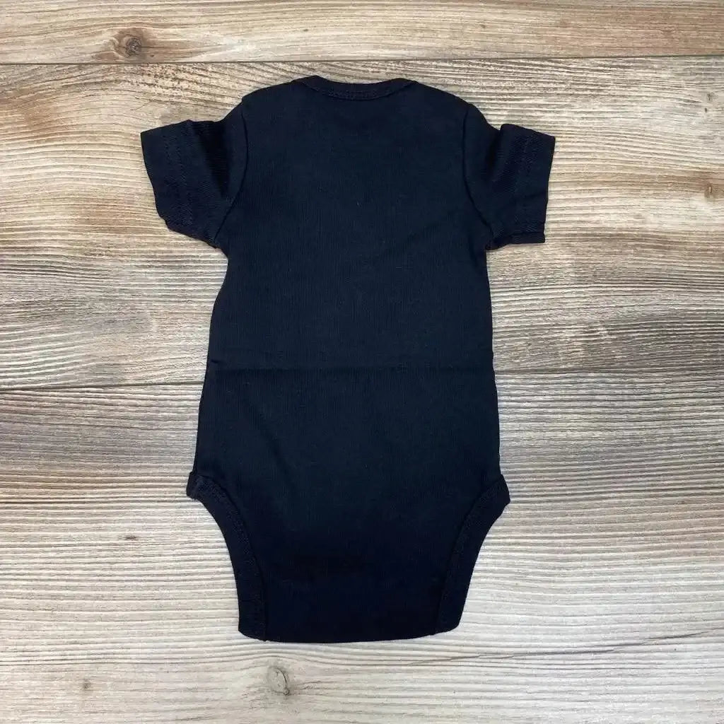 Back view of New Primary organic newborn bodysuit in black showing short sleeves and crew neckline on light wood background