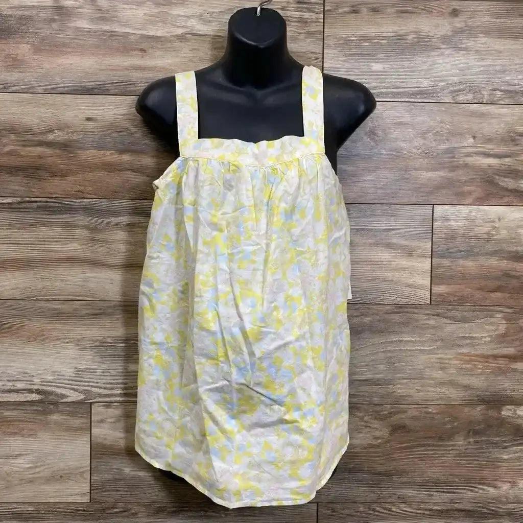 Front view of yellow floral tank top on black mannequin, wide straps, square neckline and gathered loose fit on wood wall