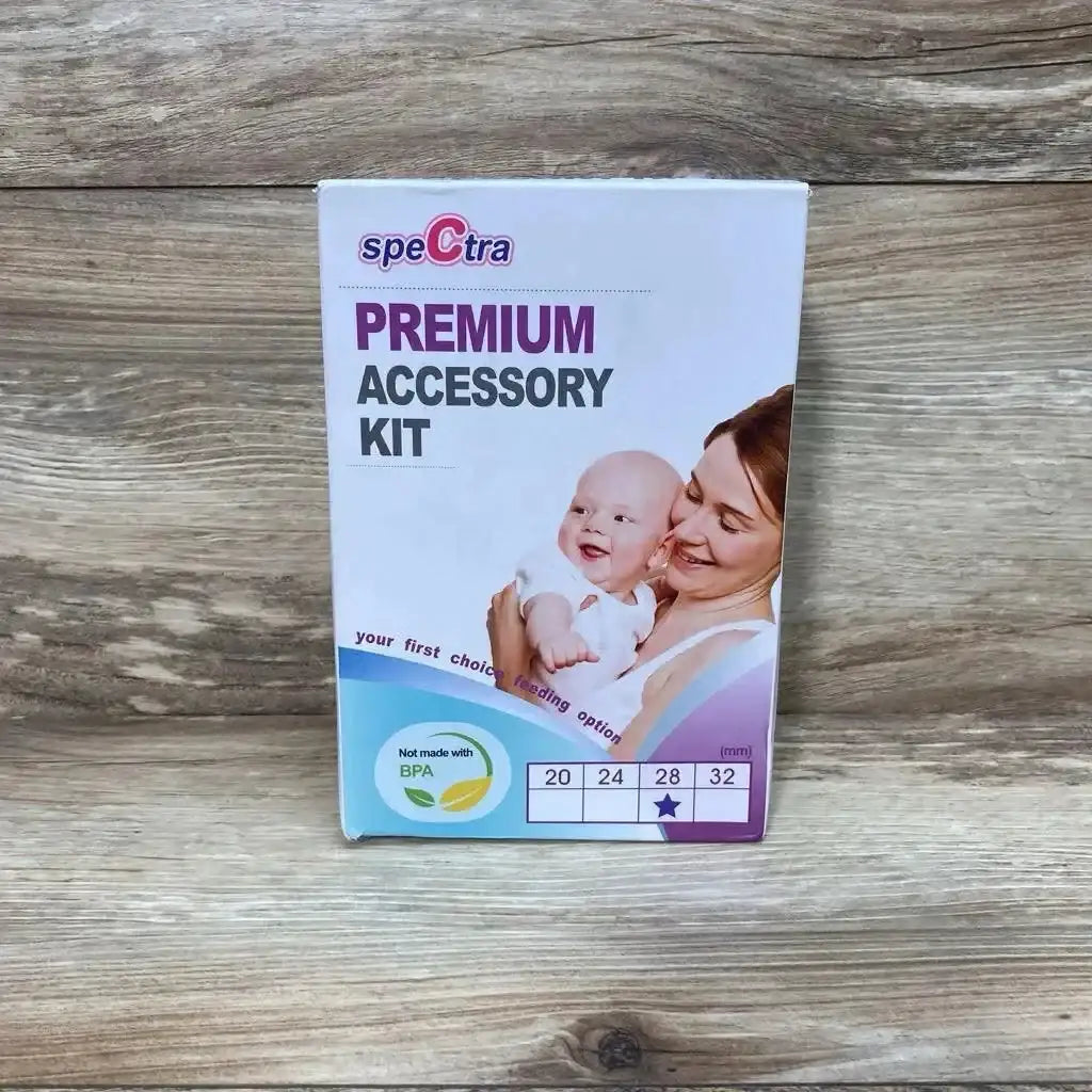 Front view of Spectra Premium 28mm breast shield accessory kit box with mother-and-baby photo and BPA-free badge on wood