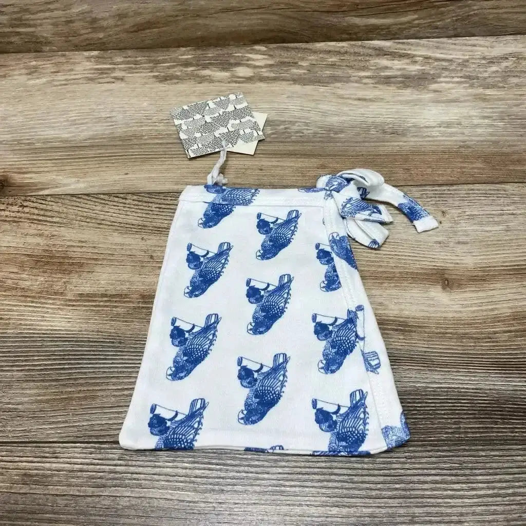 Flat lay of Kate Quinn baby elf hat (6-12m) showing blue parrot print and tied side knot on wood surface