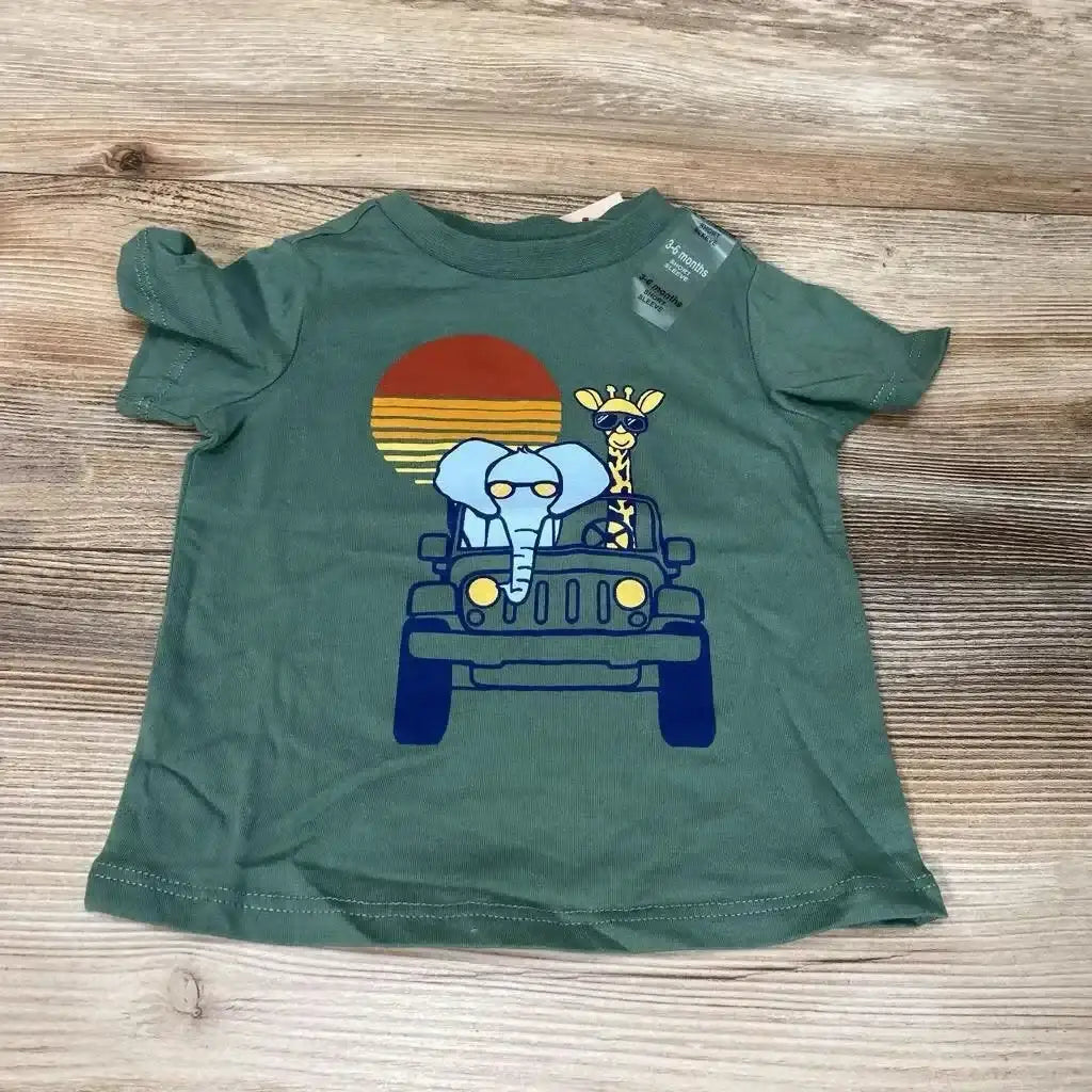 Flat lay of green 3-6 months baby t-shirt showing front Jeep with elephant and giraffe safari graphic on wood background