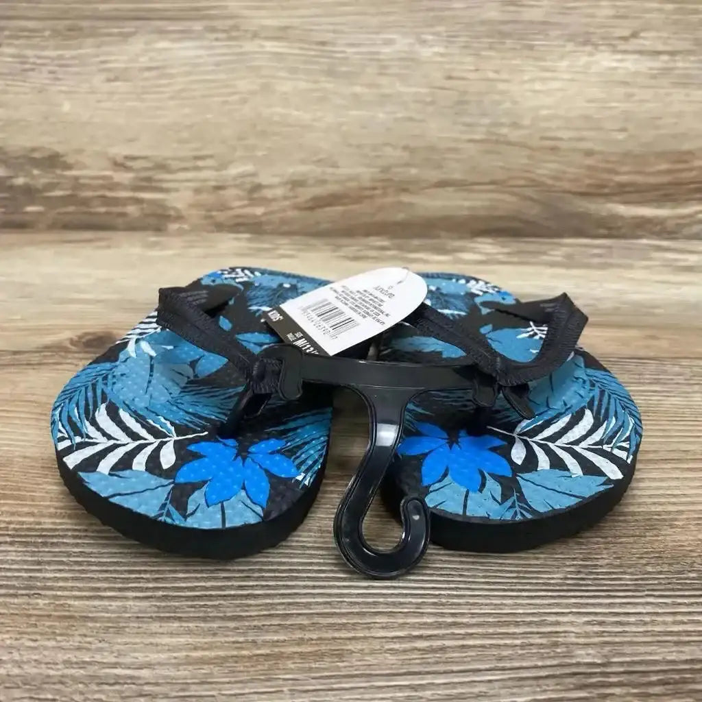 Front view of toddler blue jungle-print sandals size 13C showcasing black thong straps and tropical leaf and flower pattern on a wood surface