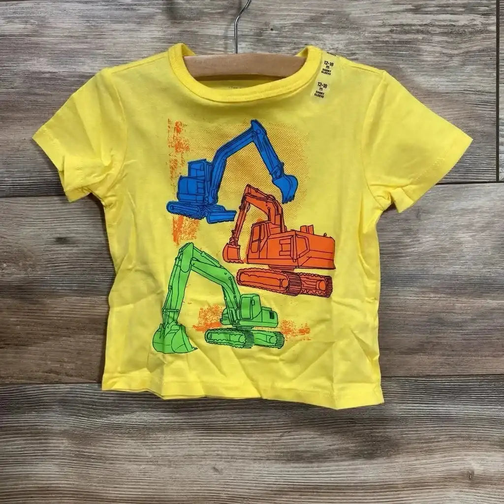 Front view yellow toddler T-shirt with three excavator graphics and size 12-18 months tag on wooden background