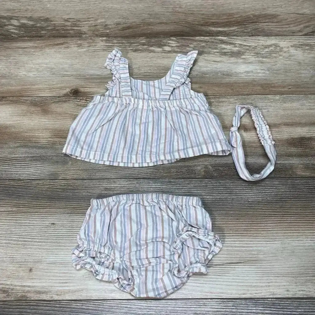 Flat lay of Carter's 3-piece striped baby set with ruffle-sleeve top, bloomers, and matching headband in pastel stripes on wood background