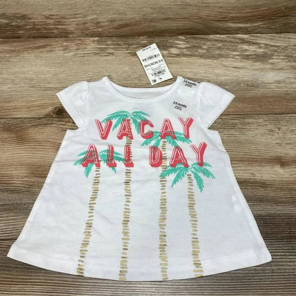 Flat lay of white First Impressions baby shirt (3-6m) showing 'VACAY ALL DAY' text and palm tree print on wood background