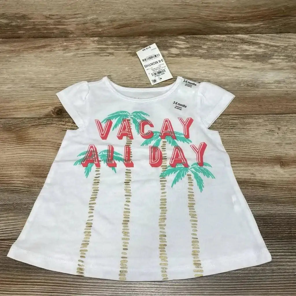 Flat lay of white First Impressions baby shirt (3-6m) showing 'VACAY ALL DAY' text and palm tree print on wood background