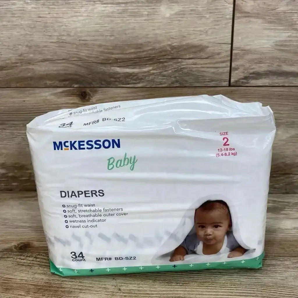 Front of McKesson baby diaper pack (size 2, 12–18 lbs, 34 count) showing brand, feature list and baby photo on wood background