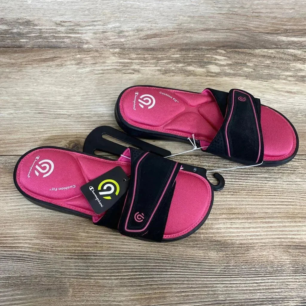Top view of pink and black toddler slide sandals showing memory-foam cushioned footbed and adjustable strap on wood