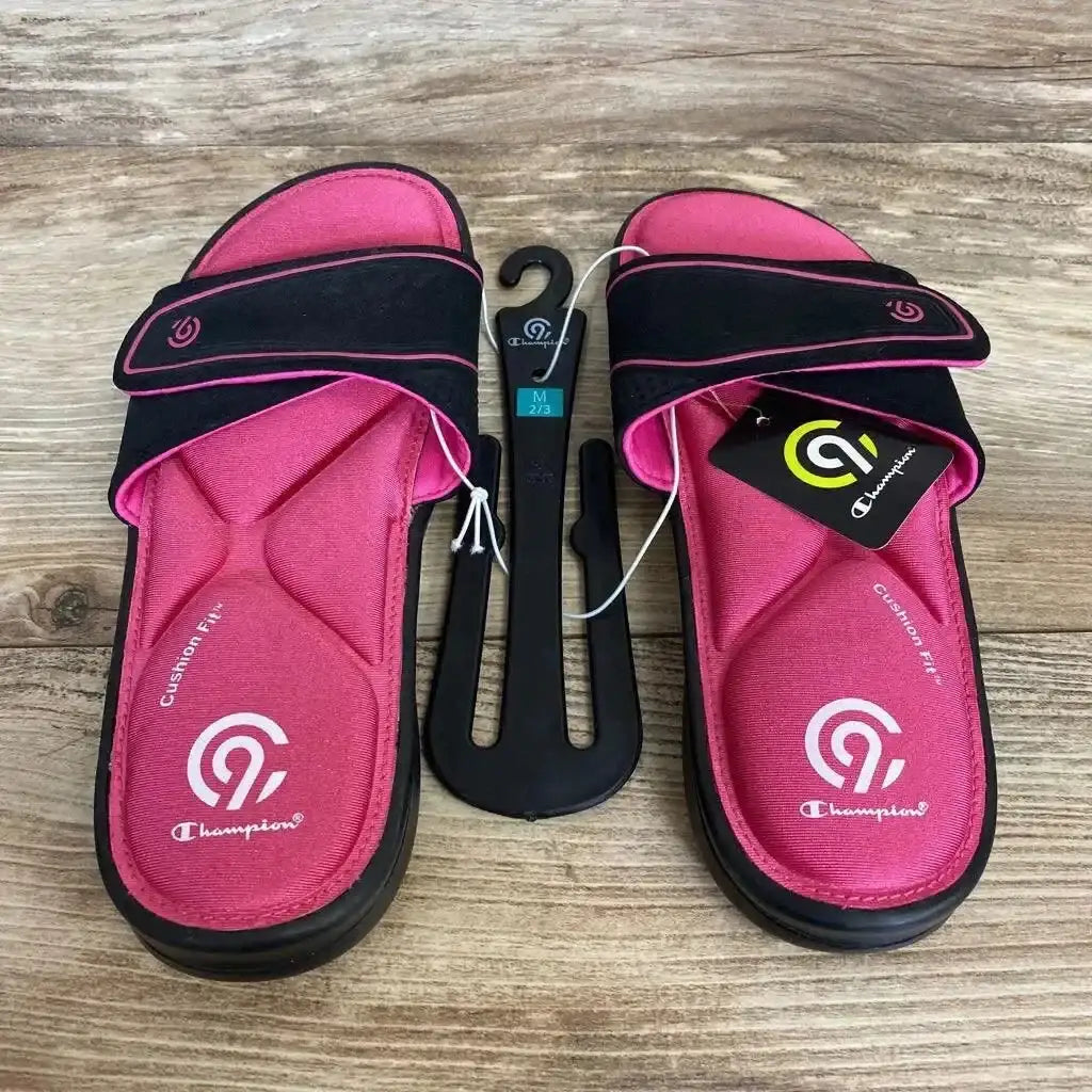 Top view of NEW C9 Champion Valma Sport Memory Foam Slide Sandals in pink and black with hangtag and shoe hanger on wood plank floor
