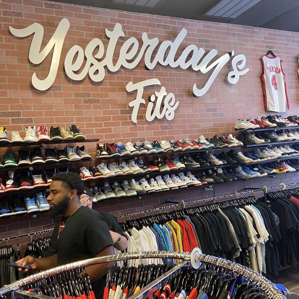 Customers browsing racks of kids clothing and rows of sneakers in a resale store beneath a brick wall sign reading Yesterday's Fits