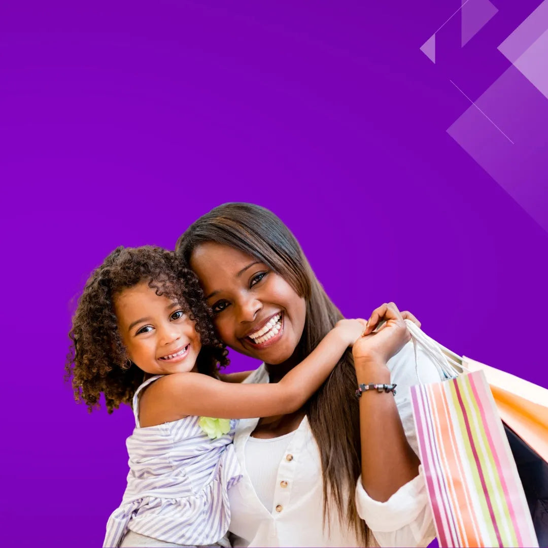 Smiling mother hugging her daughter while holding striped shopping bags against a purple background