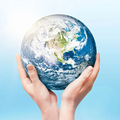 Pair of child hands holding a globe against a bright blue sky, symbolizing eco-friendly parenting