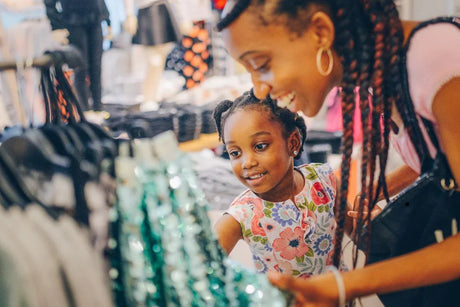 Smiling woman and girl shopping for clothes in a fashion retail store
